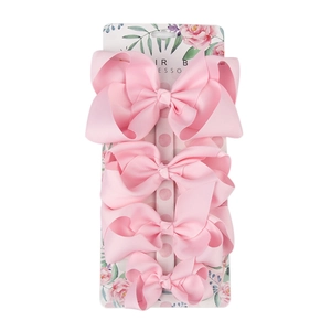 Set of four pink grosgrain ribbon hair bows in various sizes on floral display card