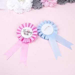Detail of Mommy To Be rosette badges in pink and blue with baby footprints design