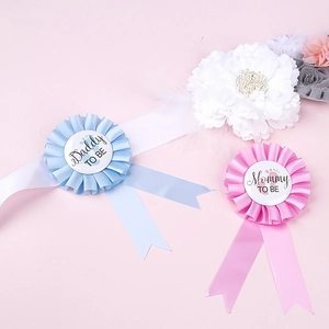 Detail of baby shower set with Mommy To Be floral sash and Daddy To Be ribbon badges