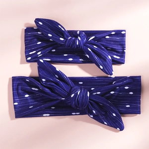 Detail view of navy blue and white polka dot bunny ear headbands on pink background