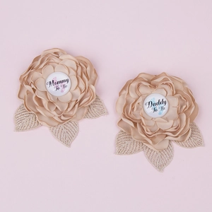 Close-up of champagne satin Mommy To Be and Daddy To Be flower badges for baby showers