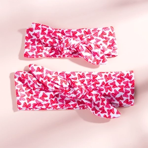 Detailed close-up of two matching red polka dot rabbit ear headbands on pink surface