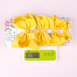 Weight measurement of four large yellow grosgrain ribbon hair bows on a digital scale