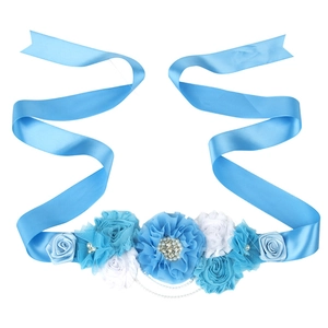Gros plan détaillé de fleurs en tissu bleu avec perles et strass sur une ceinture de maternité