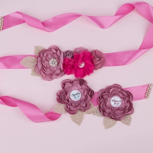 Detail of pink satin baby shower sash with Mommy To Be and Daddy To Be flower pins