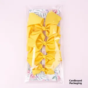 Three-piece yellow ribbon hair bows set on floral cardboard packaging for girls