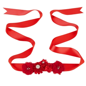 Détail d'une ceinture de maternité en satin rouge avec roses en tissu et strass étincelants