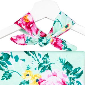 Detailed close-up of a mint green floral print baby headband tied in a bow