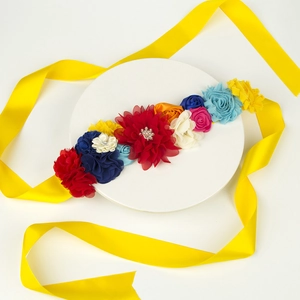 Détail de fleurs en satin colorées avec perles et strass sur une ceinture de maternité