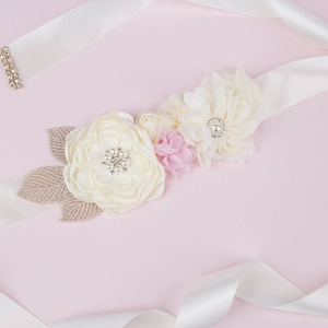 Close-up of handmade white satin maternity belt with floral fabric and pearl accents