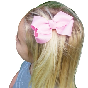Pink solid grosgrain ribbon bow hair clip for girls shown on a young toddler girl