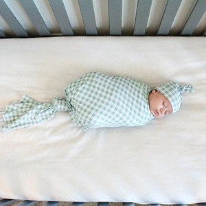 Close-up of baby swaddle set with green plaid pattern and matching top knot hat