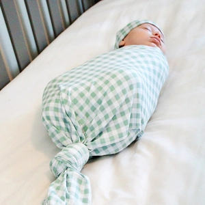 Close-up of baby in mint green gingham swaddle blanket and matching knotted beanie hat