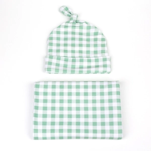Detailed view of green gingham baby swaddle blanket and matching knotted hat set
