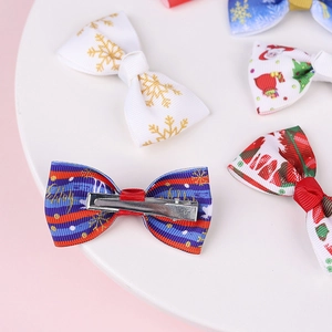 Detail view of festive Christmas bow hair clips with gold snowflake and Santa patterns