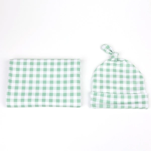 Detailed view of green gingham baby swaddle blanket and matching top knot beanie set