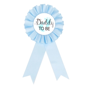 Detail of light blue Daddy TO BE rosette badge with ribbon and baby footprints