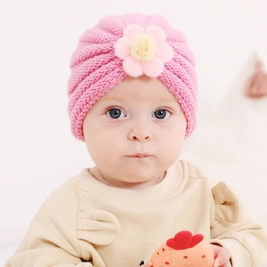 Détail d'un bonnet en tricot rose pour bébé avec fleur 3D et texture côtelée douce