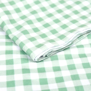 Close-up detail of green and white gingham baby swaddle fabric with white overlock edges