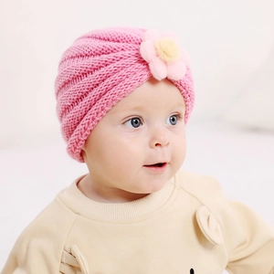 Détail d'un bonnet en tricot rose pour bébé avec texture spirale et fleur jaune douce
