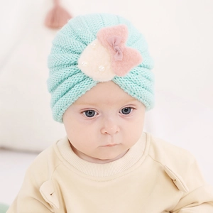 Gros plan du bonnet en tricot vert menthe pour bébé avec nœud en peluche et perles