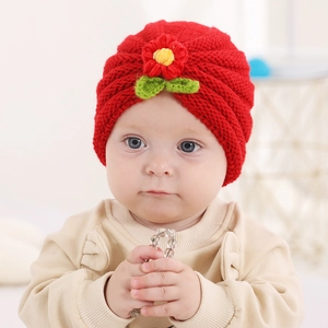 Detail of red knitted baby turban hat with delicate floral and leaf ornaments