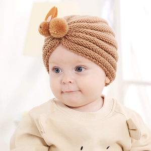 Detail view of the brown knitted baby hat featuring a cute plush bunny with pink ears