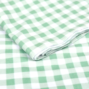 Detailed view of overlock stitching on soft green and white gingham baby swaddle fabric
