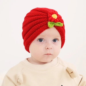 Close-up of red knitted baby turban featuring a 3D floral accent and soft yarn texture