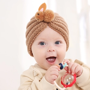 Detailed close-up of a warm knit baby hat with a cute 3D plush rabbit and crossover design