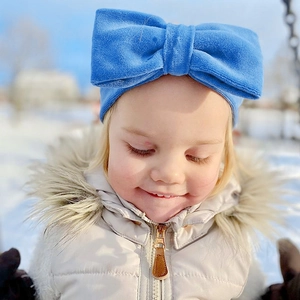 Gros plan d'un bandeau pour bébé en velours bleu roi avec un grand nœud dans une scène de neige