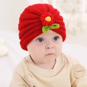 Close-up of a red knitted baby hat featuring a 3D handmade floral decoration