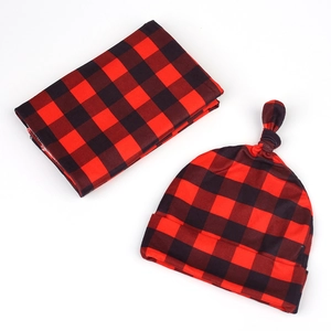 Close-up detail of soft red and black buffalo plaid baby swaddle and knotted hat set