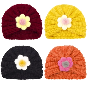 Vue détaillée de bonnets tricotés pour bébés avec fleurs colorées en quatre tons