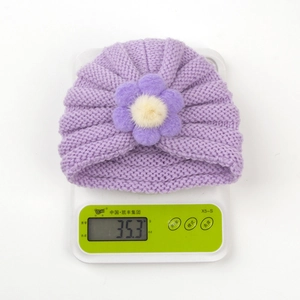 Vue détaillée du bonnet en tricot violet pour bébé pesant 35,3 g sur une balance