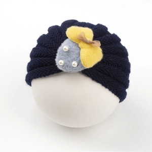 Vue détaillée du bonnet en tricot bleu foncé pour bébé avec patch en feutre et nœud