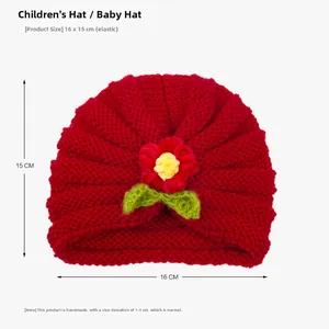 Detail of red knitted baby turban featuring handmade floral decoration and 16x15cm size