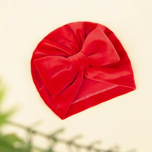 Détail de la texture en velours rouge et du grand nœud sur ce bonnet d'hiver bébé