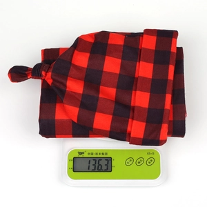 Detail shot of a buffalo plaid baby knotted hat and swaddle blanket weighing 136.3g