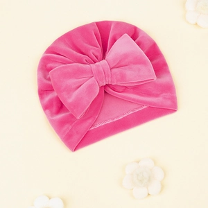 Détail du bonnet turban pour bébé en velours rose rouge avec un grand nœud décoratif
