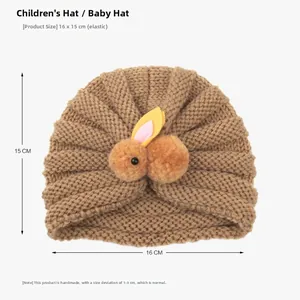 Detailed view of camel knit baby hat showing 16x15cm size and plush rabbit decor