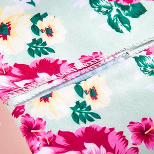 Close-up of tropical floral print fabric with precise overlock stitching detail