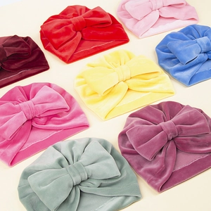 Présentation à plat de bonnets turban en velours pour bébé avec grands nœuds décoratifs