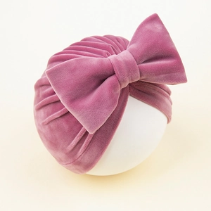 Vue détaillée du bonnet turban en velours rose foncé avec un grand nœud décoratif