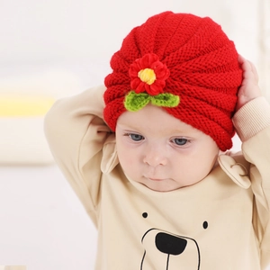 Red knit baby hat with crochet flower detail and wavy texture for warmth