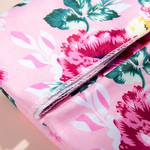 Detail of white overlock stitching on pink floral maternity robe fabric texture