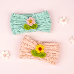 Détail de bandeaux tricotés pour bébé avec fleurs et feuilles vertes au crochet