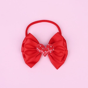 Detailed view of red grosgrain bow headband with glitter heart center for babies