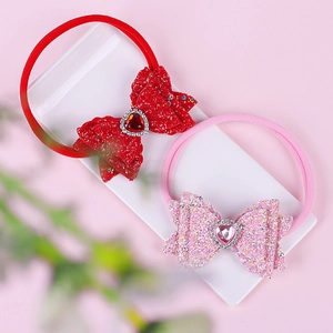 Close-up of sequin bow headbands with heart rhinestones on a white display stand
