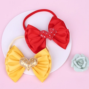 Macro view of large satin bow baby headbands with crystal heart center on display tray